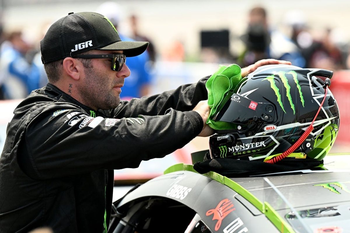 Jun 8, 2025; Brooklyn, Michigan, USA; A crew member for NASCAR Cup Series driver Tyler Reddick (45) cleans the visor on his helmet before the start of the FireKeepers Casino 400 at Michigan International Speedway. Mandatory Credit: Lon Horwedel-Imagn Images