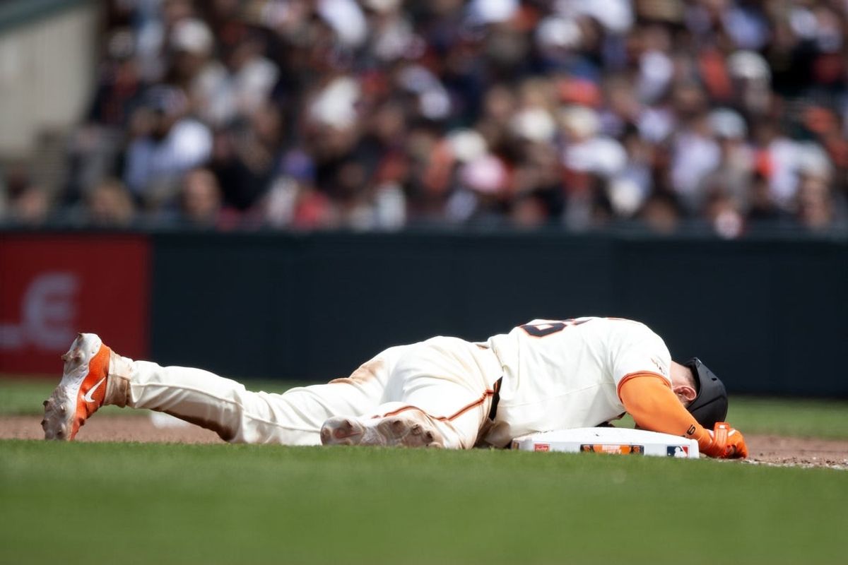 Jun 8, 2025; San Francisco, California, USA; San Francisco Giants third baseman Matt Chapman (26) lays face down in pain after being picked off first base against the Atlanta Braves during the eighth inning at Oracle Park. Chapman eventually stood, and remained in the game. Mandatory Credit: D. Ross Cameron-Imagn Images