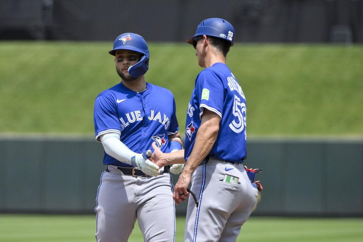 Jun 11, 2025; St. Louis, Missouri, USA;  Toronto Blue Jays shortstop Bo Bichette (11) is congratulated by first base coach Mark Budzinski (53) after hitting a one run single against the St. Louis Cardinals during the third inning at Busch Stadium. Mandatory Credit: Jeff Curry-Imagn Images
