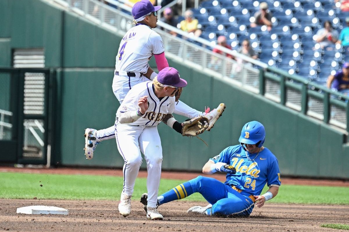 Jun 17, 2025; Omaha, Neb, USA;  LSU Tigers shortstop Steven Milam (4) completes the double play with LSU Tigers second baseman Daniel Dickinson (14) as UCLA Bruins right fielder A.J. Salgado (24) slides into the base during the sixth inning at Charles Schwab Field. Mandatory Credit: Steven Branscombe-Imagn Images