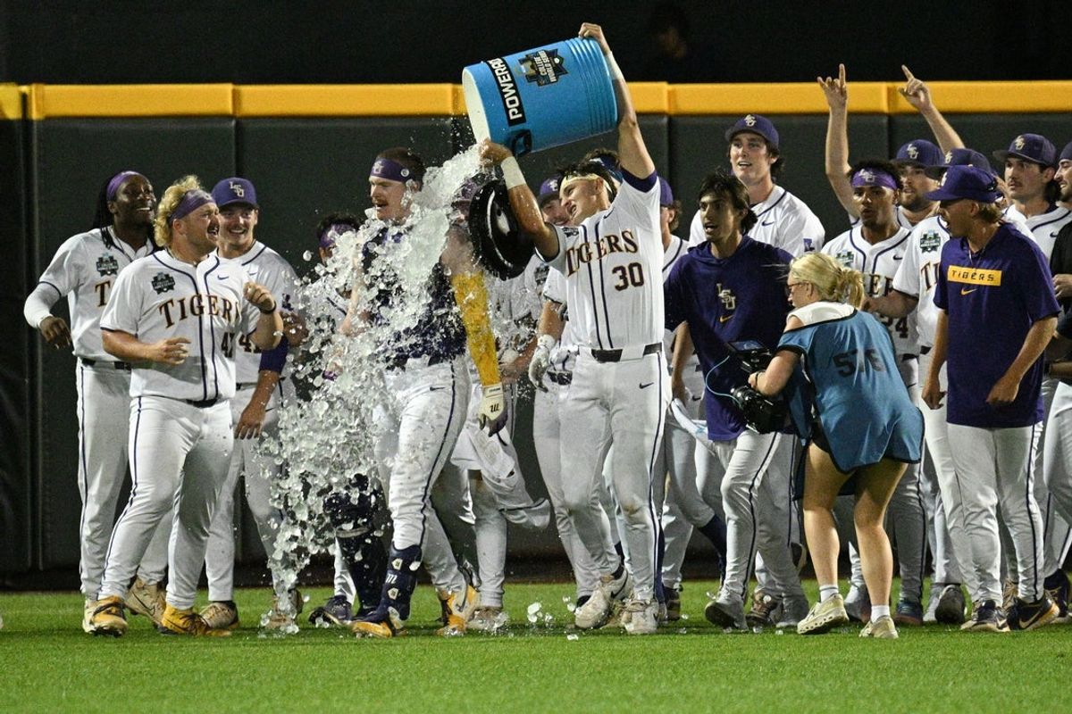 Jun 18, 2025; Omaha, Neb, USA;  LSU Tigers first baseman Jared Jones (22) receives a Powerade Bath from catcher Edward Yamin IV (30) after hitting the game winning run against the Arkansas Razorbacks at Charles Schwab Field. Mandatory Credit: Steven Branscombe-Imagn Images