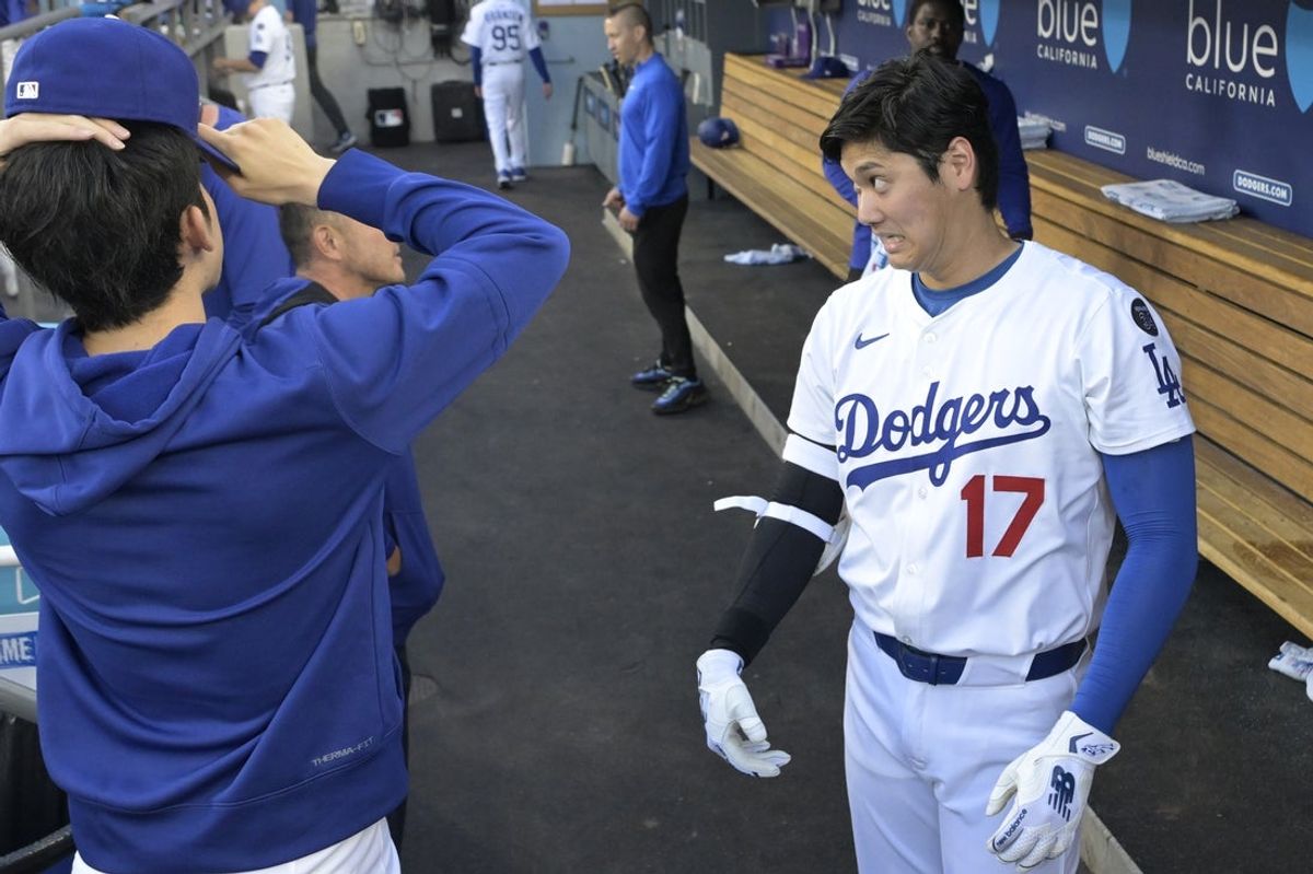 Jun 19, 2025; Los Angeles, California, USA;   Los Angeles Dodgers designated hitter Shohei Ohtani (17) laughs with starting pitche Roki Sasaki (11) and trainer Yosuke Nakajima in the dugout prior to the game against the San Diego Padres at Dodger Stadium. Mandatory Credit: Jayne Kamin-Oncea-Imagn Images
