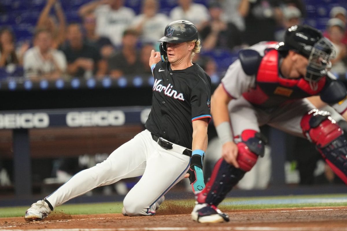 Jun 20, 2025; Miami, Florida, USA;  Miami Marlins left fielder Kyle Stowers (28) slides in safe at home plate as Atlanta Braves catcher Sean Murphy (12) gathers the late throw in the second inning at loanDepot Park. Mandatory Credit: Jim Rassol-Imagn Images