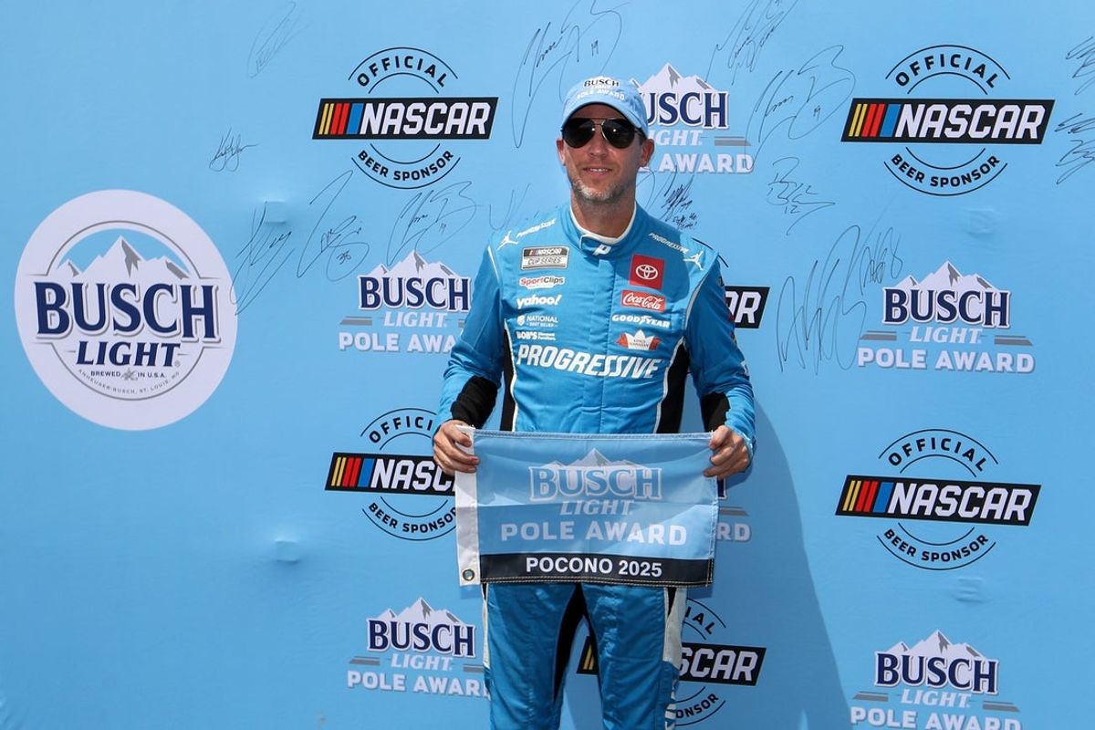 Jun 21, 2025; Long Pond, Pennsylvania, USA; NASCAR Cup Series driver Denny Hamlin stands with the Busch Light Pole Award after winning the pole for The Great American Getaway 400 at Pocono Raceway. Mandatory Credit: Matthew O'Haren-Imagn Images