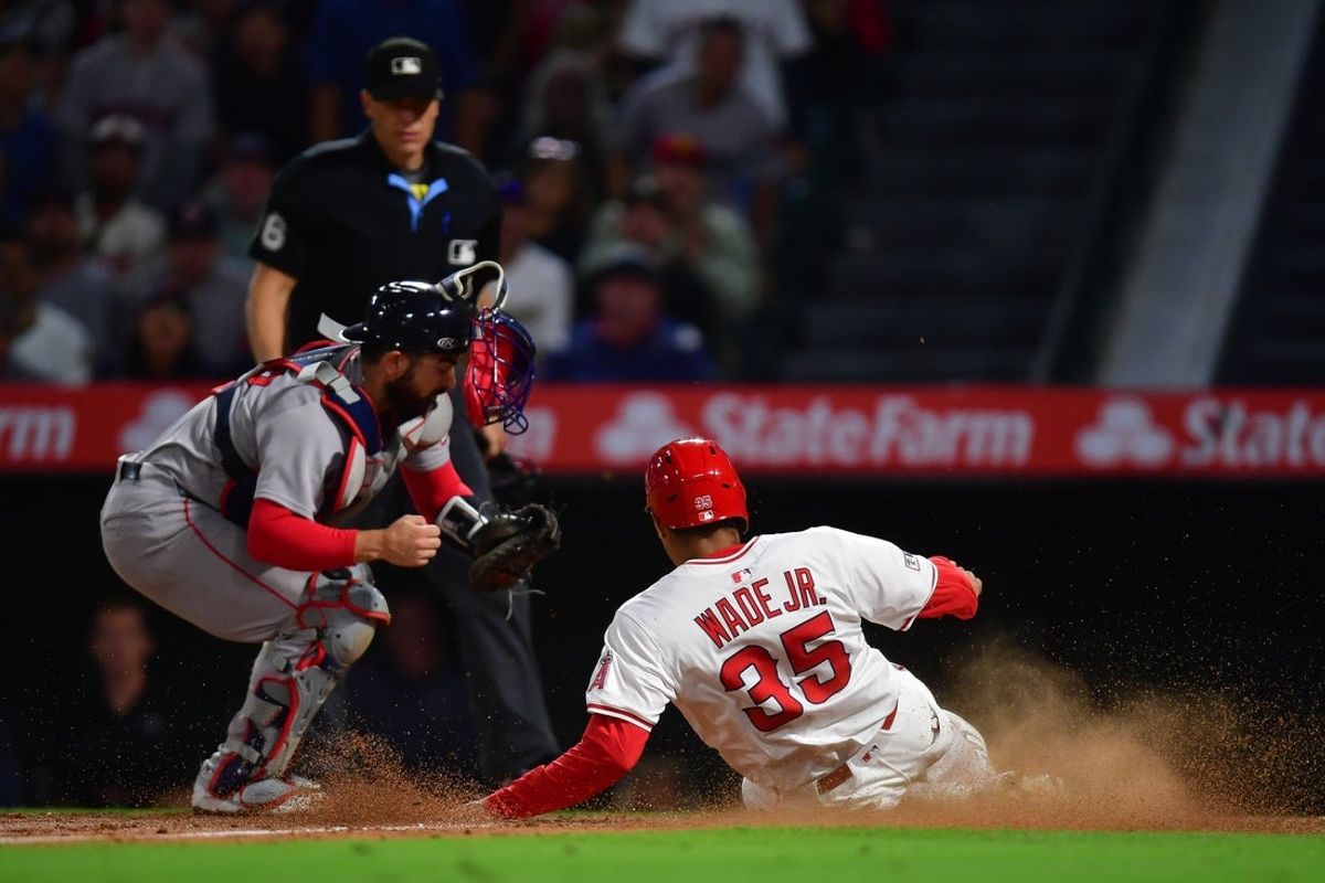Jun 23, 2025; Anaheim, California, USA; Los Angeles Angels right fielder LaMonte Wade Jr. (35) scores a run ahead of Boston Red Sox catcher Connor Wong (12) during the eighth inning at Angel Stadium. Mandatory Credit: Gary A. Vasquez-Imagn Images