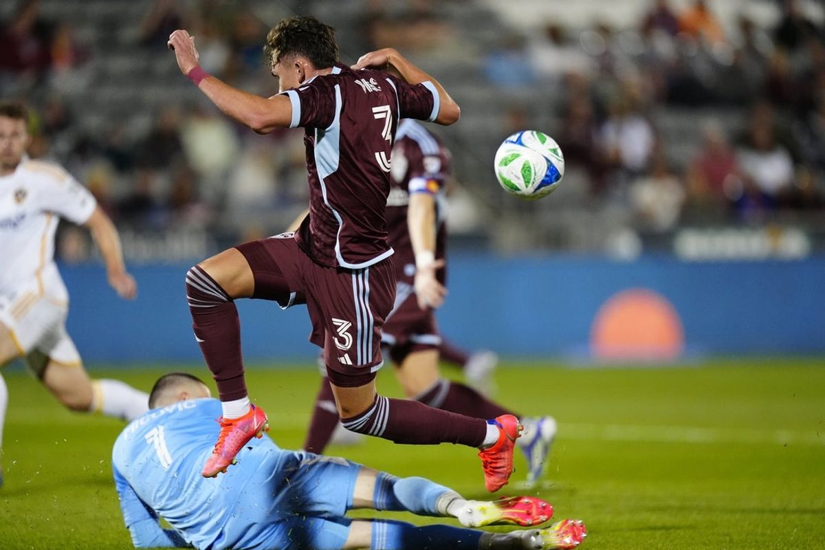 Jun 25, 2025; Commerce City, Colorado, USA; Los Angeles Galaxy goalkeeper Novak Micovic (1) makes a save on Colorado Rapids defender Sam Vines (3) in the first half at Dick's Sporting Goods Park. Mandatory Credit: Ron Chenoy-Imagn Images