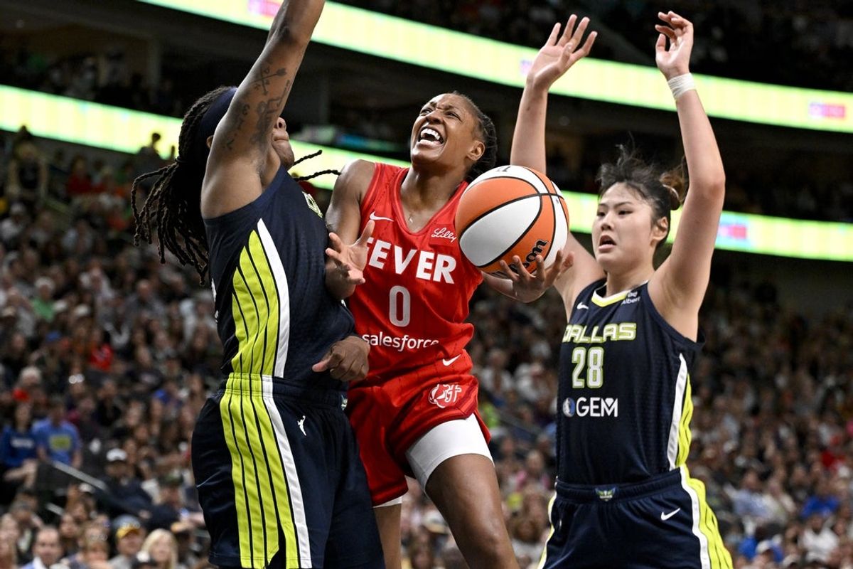 Jun 27, 2025; Dallas, Texas, USA; Indiana Fever guard Kelsey Mitchell (0) drives to the basket between Dallas Wings forward Myisha Hines-Allen (2) and center Li Yueru (28) during the second half at the American Airlines Center. Mandatory Credit: Jerome Miron-Imagn Images
