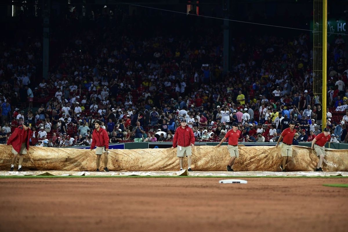 Jul 1, 2025; Boston, Massachusetts, USA;  Boston Red Sox grounds crew pulls the tarp on the field during a rain delay in the third inning against the Cincinnati Reds at Fenway Park. Mandatory Credit: Bob DeChiara-Imagn Images
