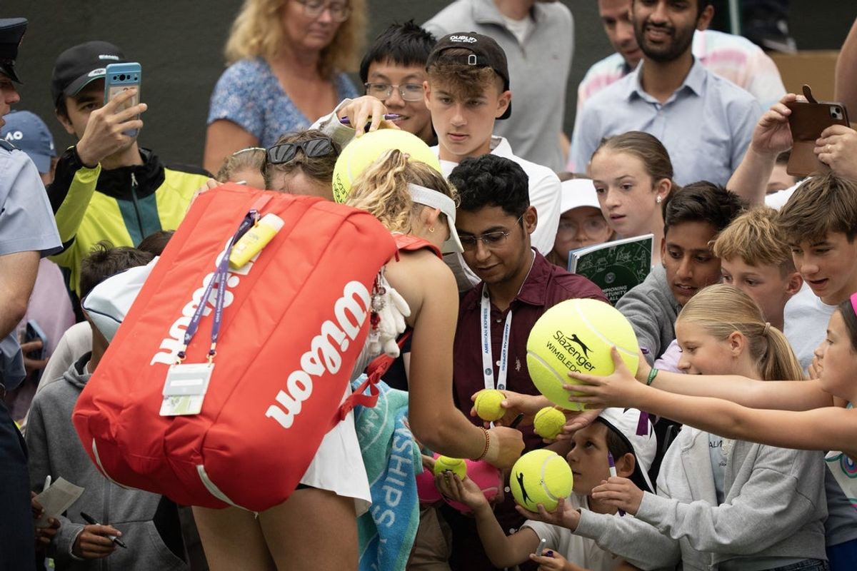 Jul 5, 2025; Wimbledon, United Kingdom;  Mirra Andreeva signs autographs for tennis fans after her match against Hailey Baptiste of the United States on day six at the All England Lawn Tennis and Croquet Club. Mandatory Credit: Susan Mullane-Imagn Images