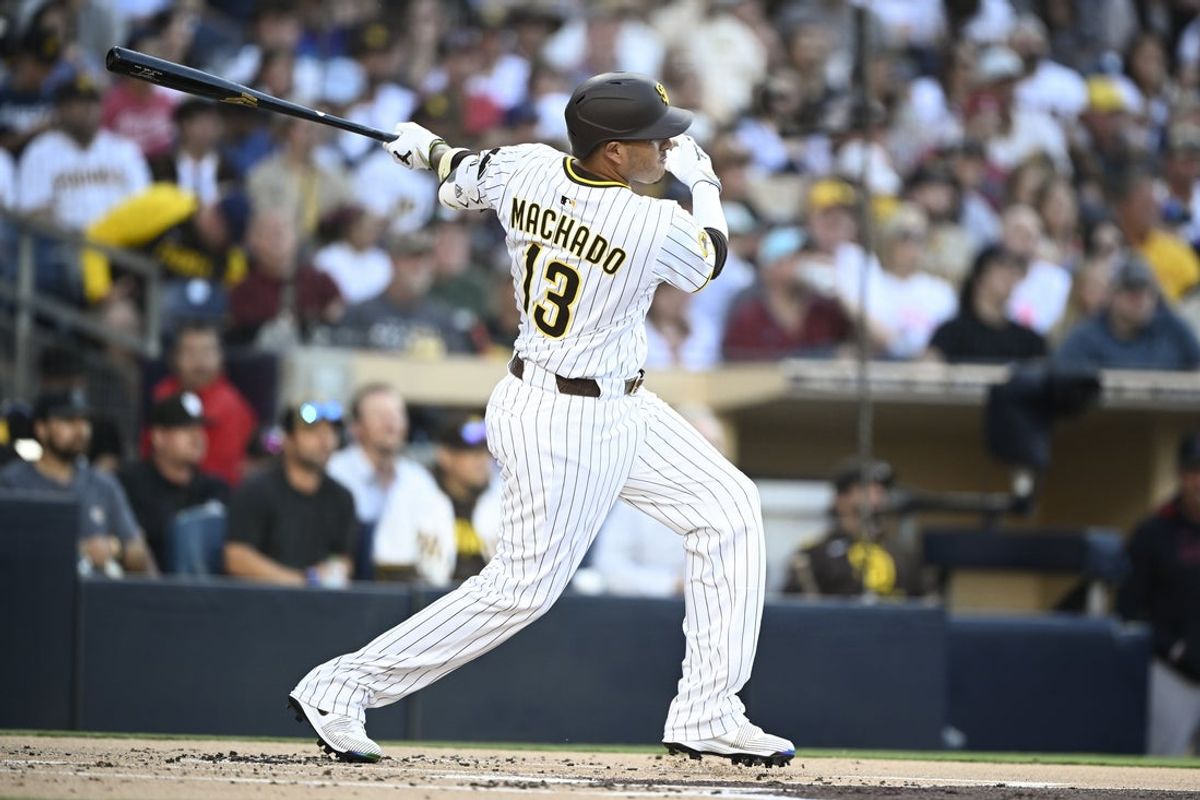Jul 7, 2025; San Diego, California, USA; San Diego Padres third baseman Manny Machado (13) hits a single during the first inning against the Arizona Diamondbacks at Petco Park. Mandatory Credit: Denis Poroy-Imagn Images