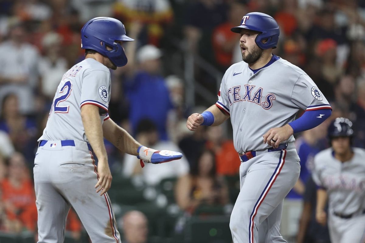 Jul 11, 2025; Houston, Texas, USA; Texas Rangers center fielder Evan Carter (32) and first baseman Jake Burger (21) score on an RBI double by designated hitter Jonah Heim (not pictured) during the third inning against the Houston Astros at Daikin Park. Mandatory Credit: Troy Taormina-Imagn Images