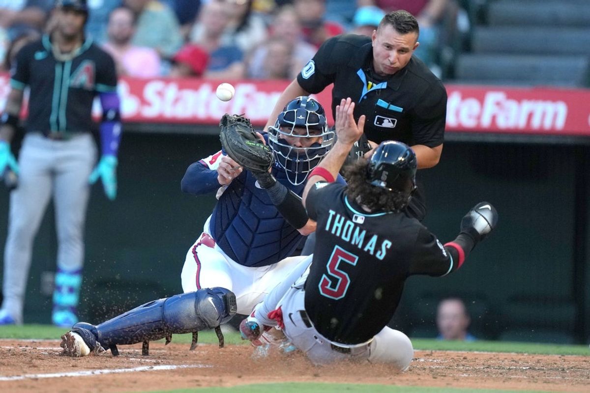 Jul 11, 2025; Anaheim, California, USA; Arizona Diamondbacks right fielder Randal Grichuk (15) slides into home plate  to beat a throw to Los Angeles Angels catcher Logan O'Hoppe (14) as home plate umpire Jonathan Parra makes the call in the second inning at Angel Stadium. Mandatory Credit: Kirby Lee-Imagn Images