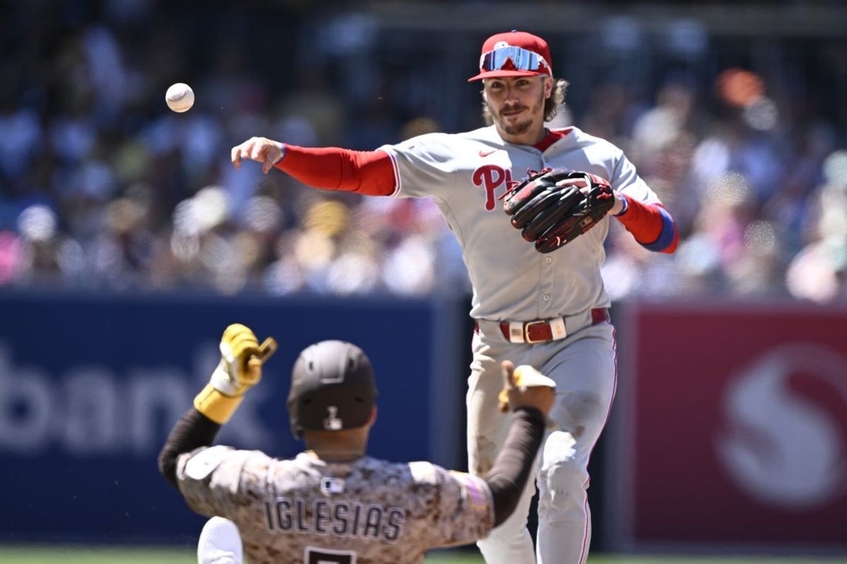 Jul 13, 2025; San Diego, California, USA; Philadelphia Phillies second baseman Bryson Stott (5) throws over San Diego Padres second baseman Jose Iglesias (7) as he turns a double play during the sixth inning at Petco Park. Mandatory Credit: Denis Poroy-Imagn Images
