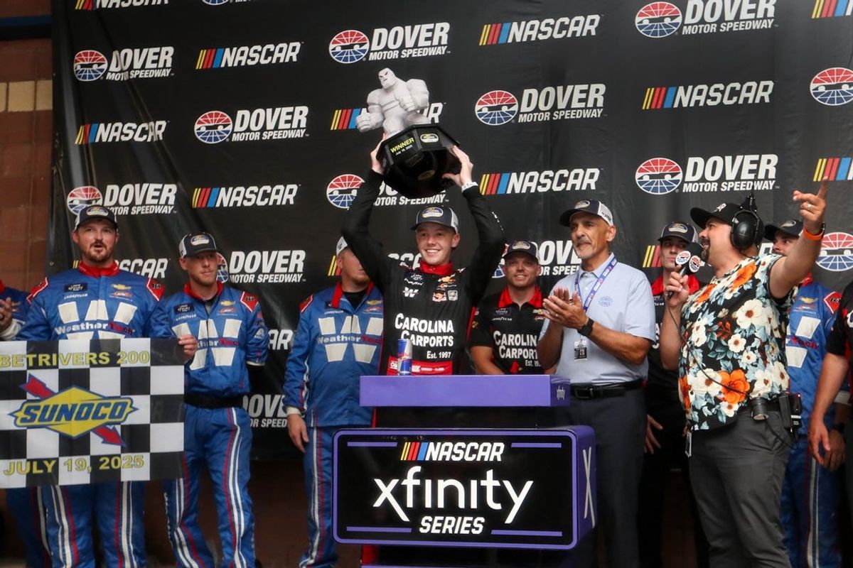Jul 19, 2025; Dover, Delaware, USA; NASCAR Xfinity Series driver Connor Zilisch raises the winner’s trophy in victory lane after winning the BetRivers 200 at Dover Motor Speedway. Mandatory Credit: Matthew O'Haren-Imagn Images