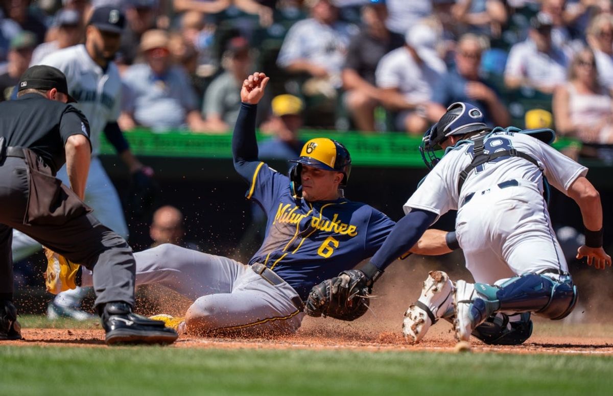 Jul 23, 2025; Seattle, Washington, USA;  Milwaukee Brewers left fielder Isaac Collins (6) slides safely into home plate to score run ahead of a tag by Seattle Mariners catcher Mitch Garver (18) during the fourth inning at T-Mobile Park. Mandatory Credit: Stephen Brashear-Imagn Images