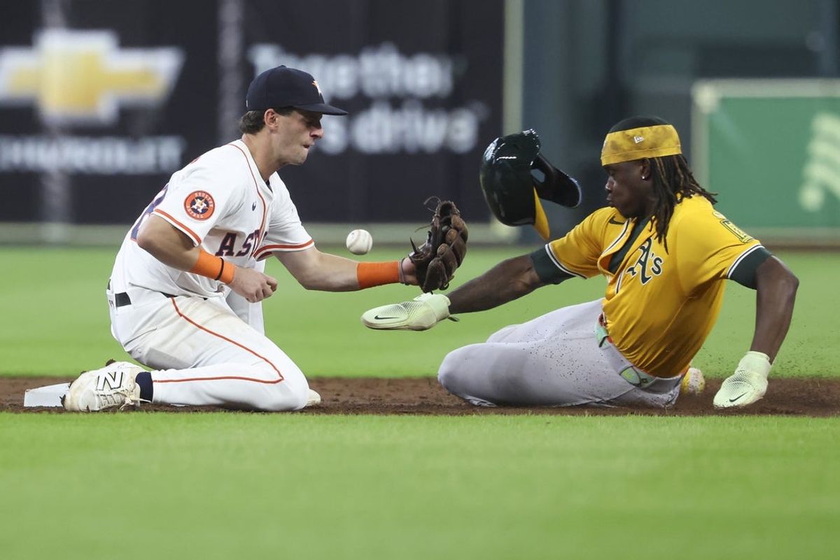 Jul 24, 2025; Houston, Texas, USA;  Athletics center fielder Lawrence Butler (4) is safe at second base with a stolen base as Houston Astros shortstop Zack Short (38) fields a throw during the second inning at Daikin Park. Mandatory Credit: Troy Taormina-Imagn Images