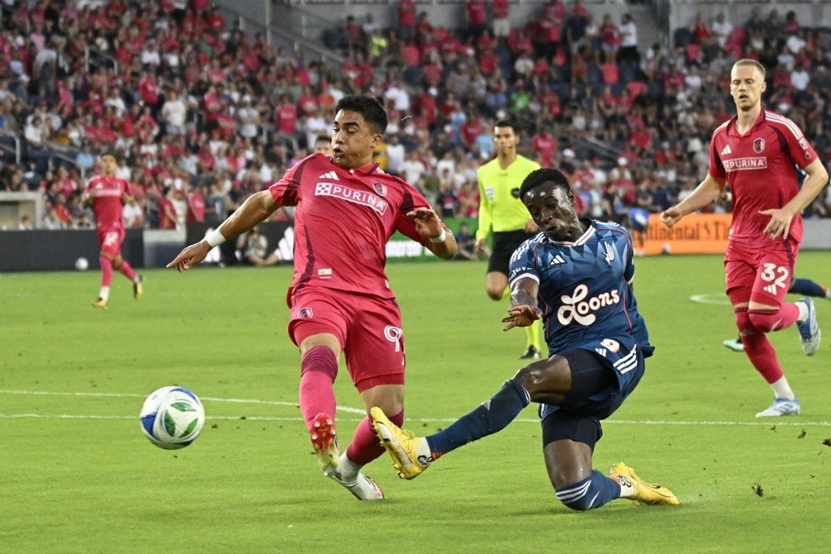 Jul 26, 2025; St. Louis, Missouri, USA; Minnesota United midfielder Joseph Rosales (8) takes a shot as St. Louis City Jaziel Orozco (91) defends at Energizer Park. Mandatory Credit: Scott Rovak-Imagn Images