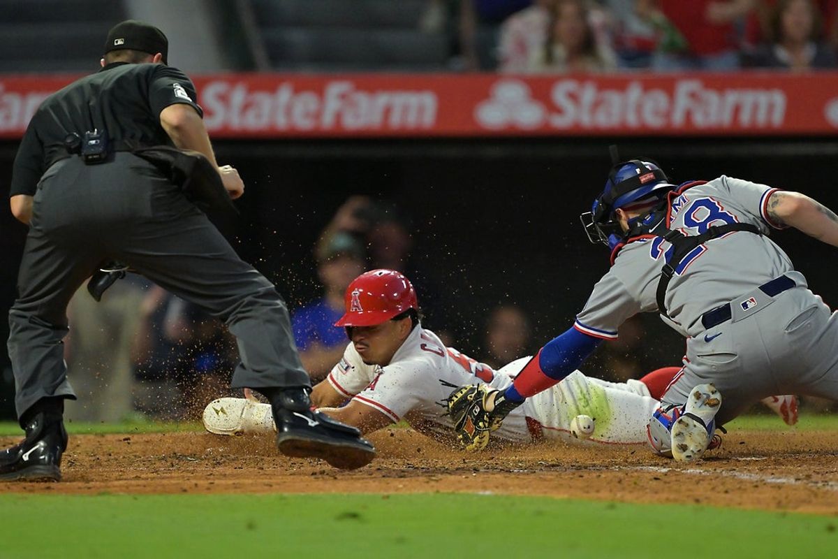 Jul 28, 2025; Anaheim, California, USA;  Los Angeles Angels right fielder Gustavo Campero (51) scores past Texas Rangers catcher Jonah Heim (28) on a double by Los Angeles Angels shortstop Zach Neto (9) during the fifth inning at Angel Stadium. Mandatory Credit: Jayne Kamin-Oncea-Imagn Images