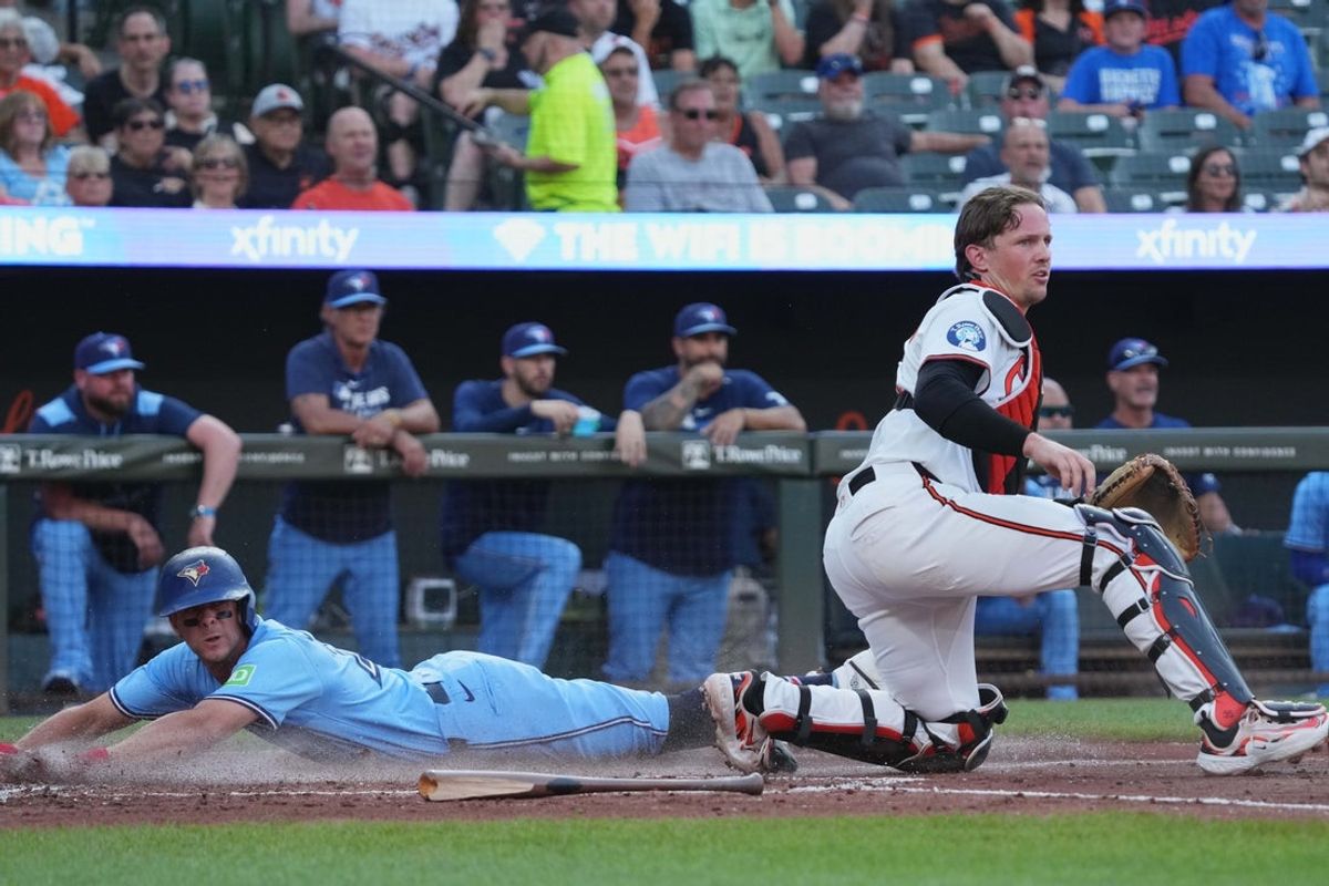 Jul 29, 2025; Baltimore, Maryland, USA; Toronto Blue Jays shortstop Ernie Clement (22) slides past Baltimore Orioles catcher Adley Rutschman (35) to score during the second inning at Oriole Park at Camden Yards. Mandatory Credit: Mitch Stringer-Imagn Images