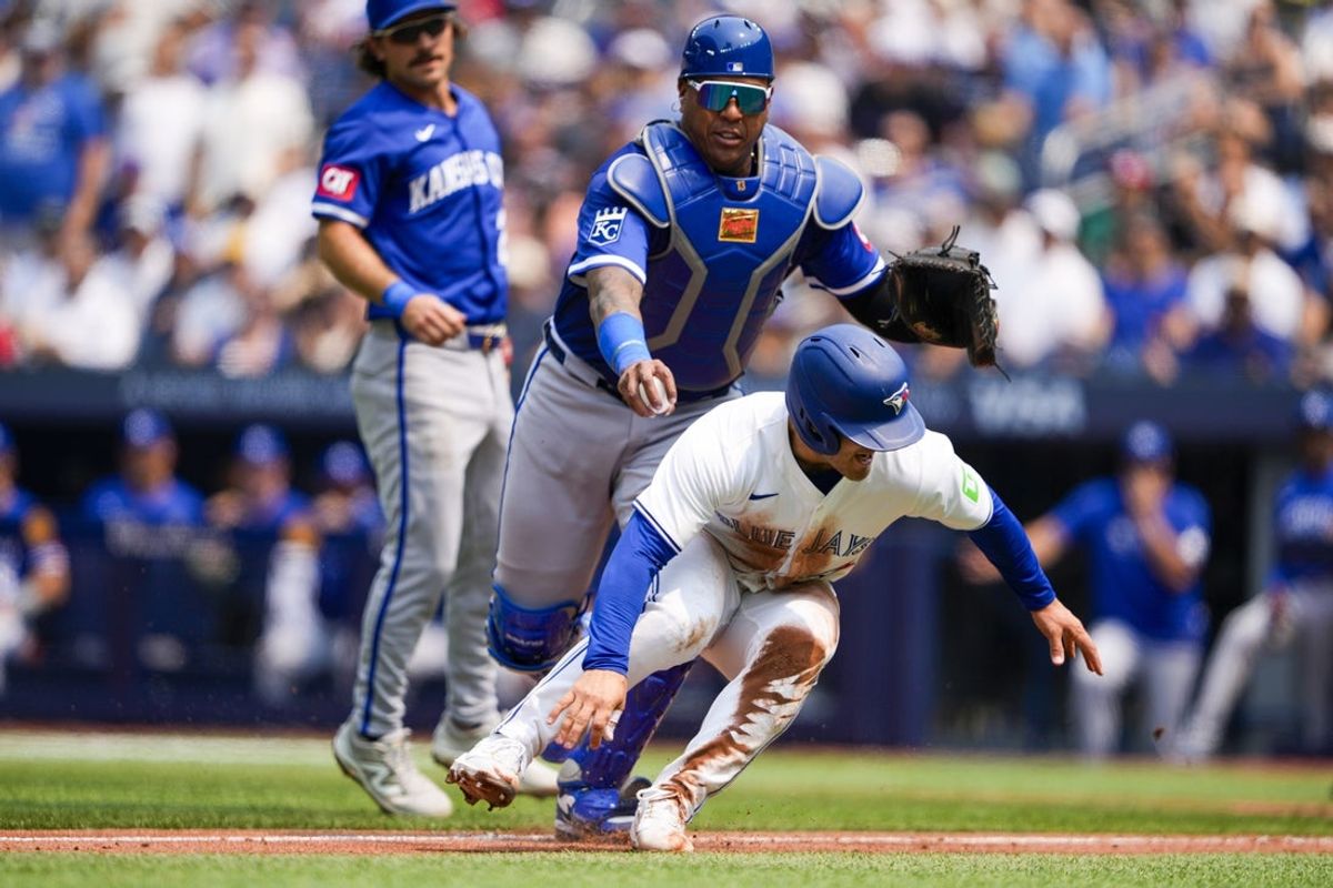 Aug 3, 2025; Toronto, Ontario, CAN; Toronto Blue Jays outfielder Daulton Barsho (5) attempts to avoid the tag by Kansas City Royals catcher Salvador Perez (13) during the second inning at Rogers Centre. Mandatory Credit: Kevin Sousa-Imagn Images