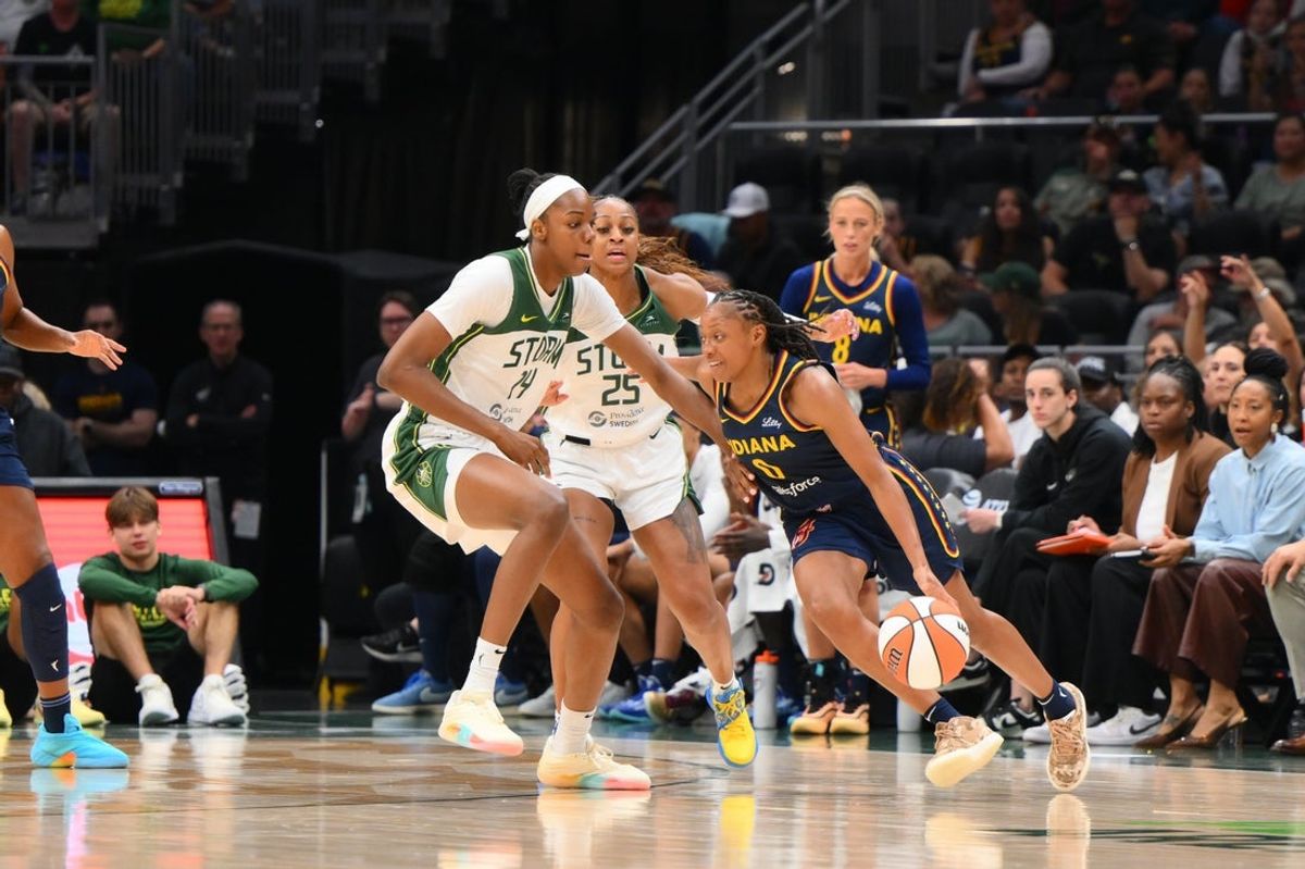 Aug 3, 2025; Seattle, Washington, USA; Indiana Fever guard Kelsey Mitchell (0) plays the ball while guarded by Seattle Storm center Dominique Malonga (14) during the first half at Climate Pledge Arena. Mandatory Credit: Steven Bisig-Imagn Images