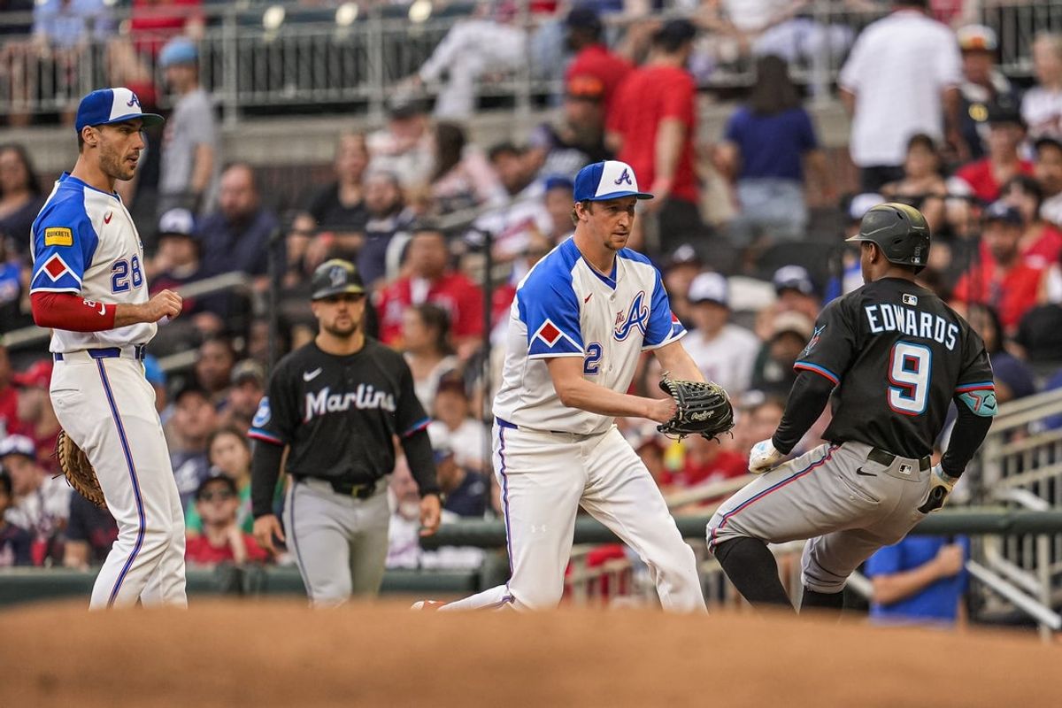 Aug 9, 2025; Cumberland, Georgia, USA; Atlanta Braves starting pitcher Erick Fedde (22) tags out Miami Marlins shortstop Xavier Edwards (9) after fielding a ground ball during the third inning at Truist Park. Mandatory Credit: Dale Zanine-Imagn Images