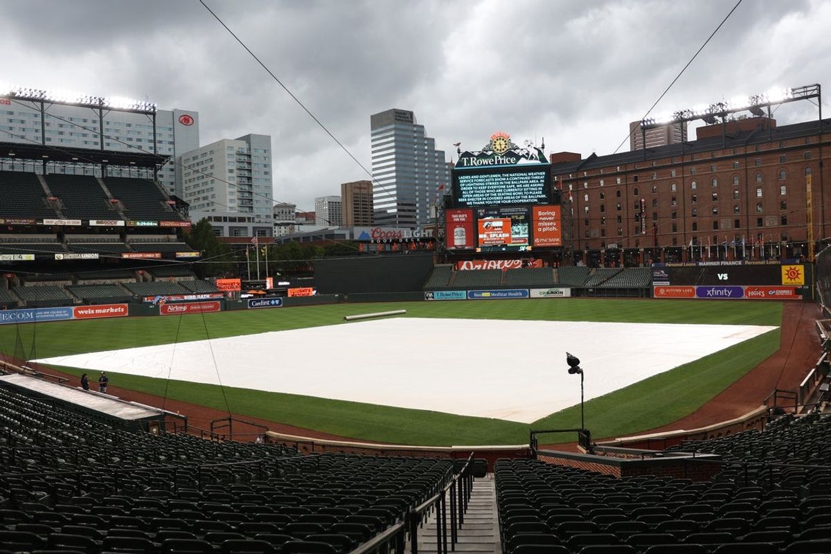 Aug 13, 2025; Baltimore, Maryland, USA; A warning for inclement weather is displayed on the scoreboard as a rain tarp covers thefield before a game between the Baltimore Orioles and the Seattle Mariners at Oriole Park at Camden Yards. Mandatory Credit: Daniel Kucin Jr.-Imagn Images
