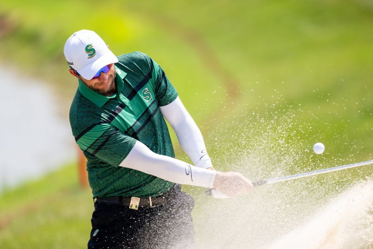 Aug 15, 2025; Indianapolis, IN, United States; Dean Burmester of Stinger GC hits a ball out of the sand on the 5th hole during the first round of LIV Golf Indianapolis. Mandatory Credit: Marc Lebryk-Imagn Images