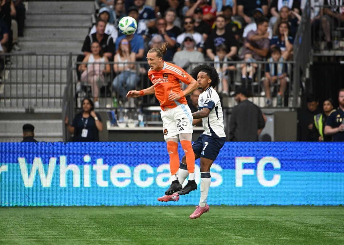 Aug 17, 2025; Vancouver, British Columbia, CAN; Houston Dynamo FC midfielder Griffin Dorsey (25) heads the ball away from Vancouver Whitecaps FC forward Jayden Nelson (7) during the second half at BC Place. Mandatory Credit: Simon Fearn-Imagn Images