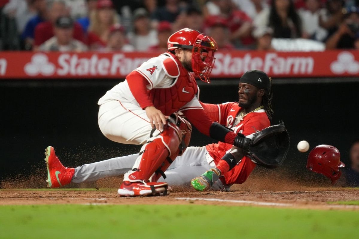 Aug 19, 2025; Anaheim, California, USA; Cincinnati Reds shortstop Elly De La Cruz (44) beats a throw to Los Angeles Angels catcher Travis d'Arnaud (25) to score in the fifth inning  at Angel Stadium. Mandatory Credit: Kirby Lee-Imagn Images