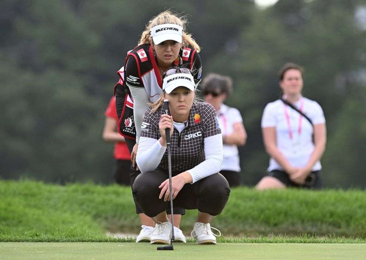 Aug 23, 2025; Mississauga, Ontario, CAN;  Brooke Henderson lines up a putt with her sister and caddie Brittany Henderson at the 18th green during third round play at the CPKC Women's Open golf tournament. Mandatory Credit: Dan Hamilton-Imagn Images
