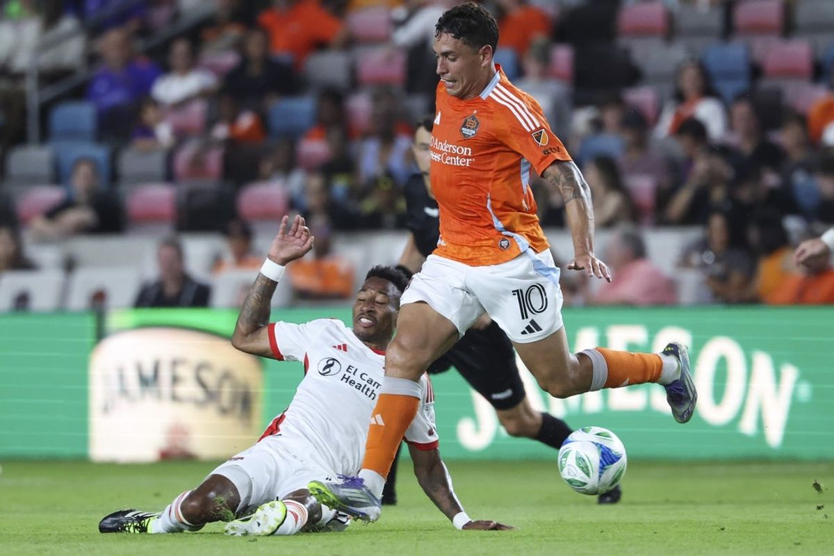 Aug 23, 2025; Houston, Texas, USA; San Jose Earthquakes midfielder Mark-Anthony Kaye (14) attempts a slide tackle against Houston Dynamo FC forward Ezequiel Ponce (10) during the first half at Shell Energy Stadium. Mandatory Credit: Troy Taormina-Imagn Images