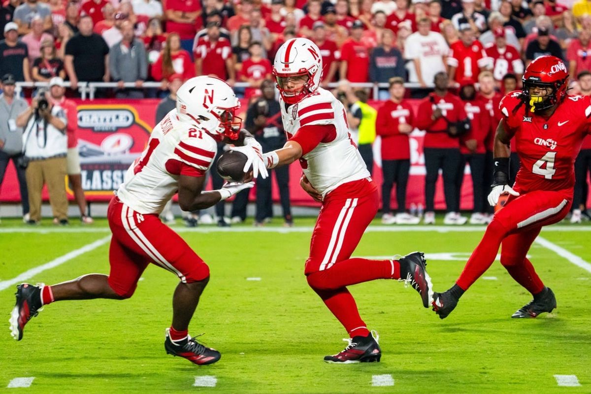 Aug 28, 2025; Kansas City, Missouri, USA; Nebraska Cornhuskers quarterback Dylan Raiola (15) hands the ball off to running back Emmett Johnson (21) against Cincinnati Bearcats defensive lineman Mikah Coleman (4) during the first quarter at GEHA Field at Arrowhead Stadium. Mandatory Credit: Dylan Widger-Imagn Images