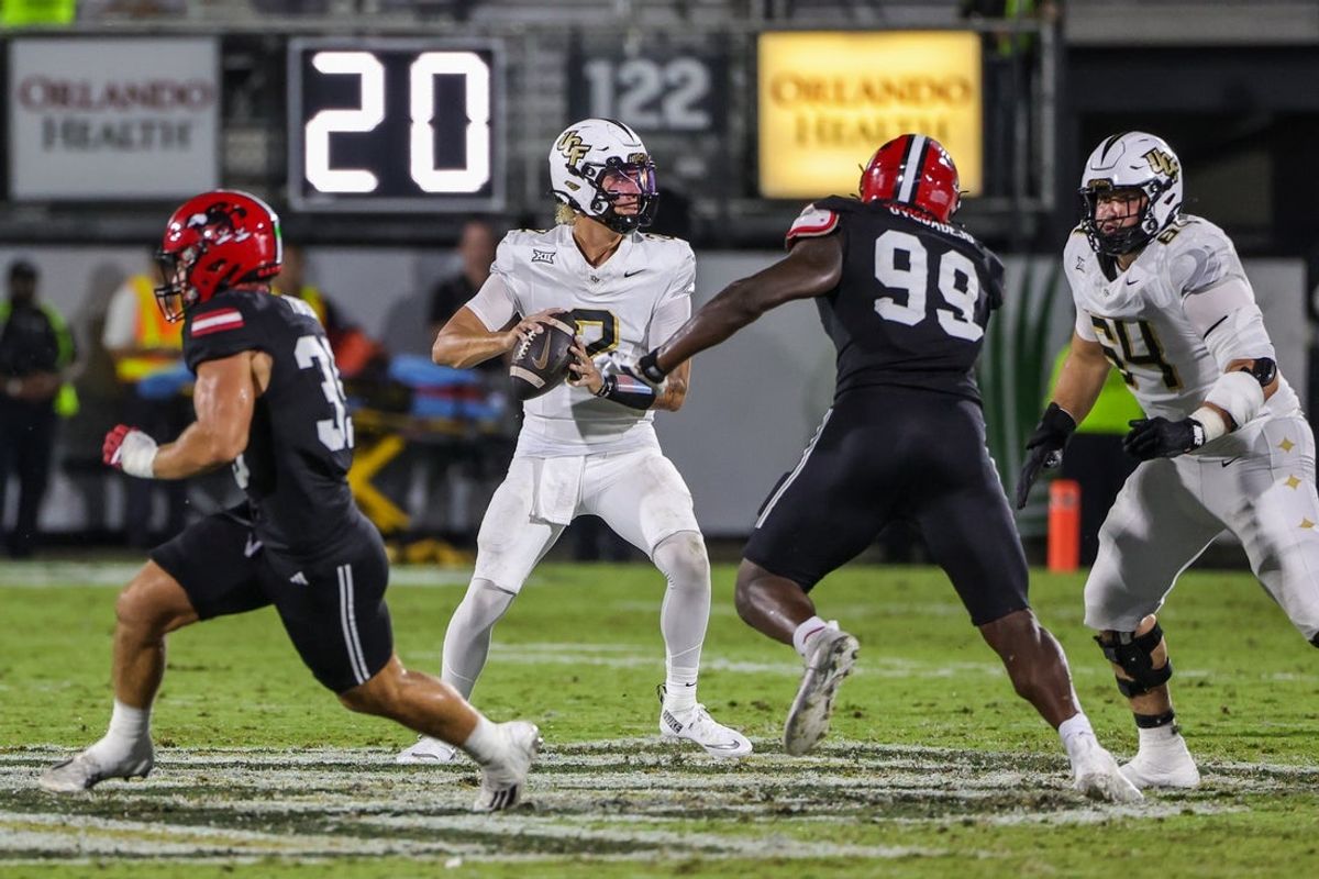 Aug 28, 2025; Orlando, Florida, USA; UCF Knights quarterback Tayven Jackson (2) rolls back to pass as Jacksonville State Gamecocks defensive end Emmanuel Oyebadejo (99) moves in during the second quarter at Acrisure Bounce House. Mandatory Credit: Mike Watters-Imagn Images