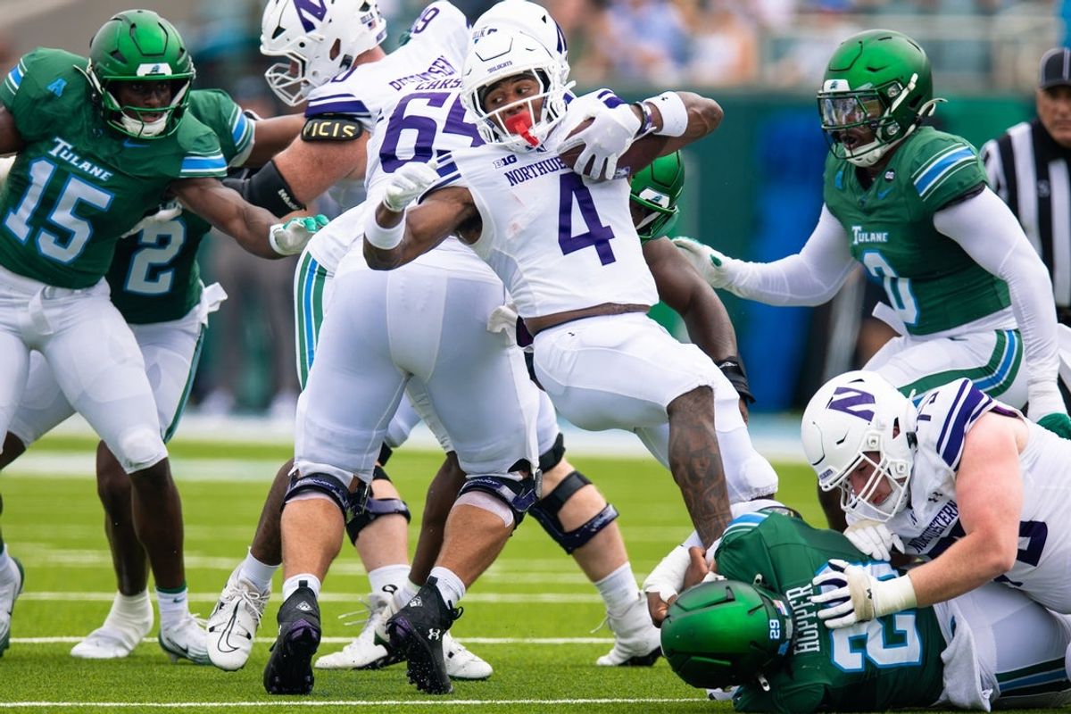 Aug 30, 2025; New Orleans, Louisiana, USA; Northwestern Wildcats running back Cam Porter (4) is tackled by Tulane Green Wave defensive lineman Santana Hopper (29) during the first half at Yulman Stadium. Mandatory Credit: Stephen Lew-Imagn Images
