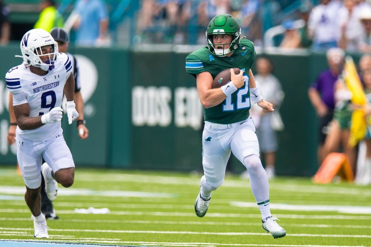 Aug 30, 2025; New Orleans, Louisiana, USA; Editors Notes:Caption Correction) Tulane Green Wave quarterback Jake Ratzlaff (12)  rushes for a touchdown against Northwestern Wildcats defensive back Braden Turner (9) during the first half at Yulman Stadium. Mandatory Credit: Stephen Lew-Imagn Images