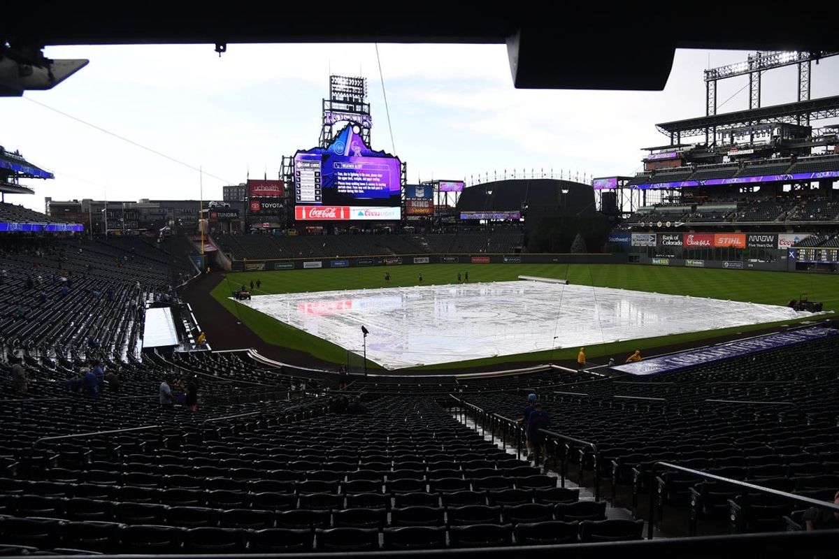 Aug 30, 2025; Denver, Colorado, USA; Members of the grounds crew prepare to remove the tarp from the field after a 20 minute weather delay before the game between the Colorado Rockies and the Chicago Cubs at Coors Field. Mandatory Credit: Christopher Hanewinckel-Imagn Images