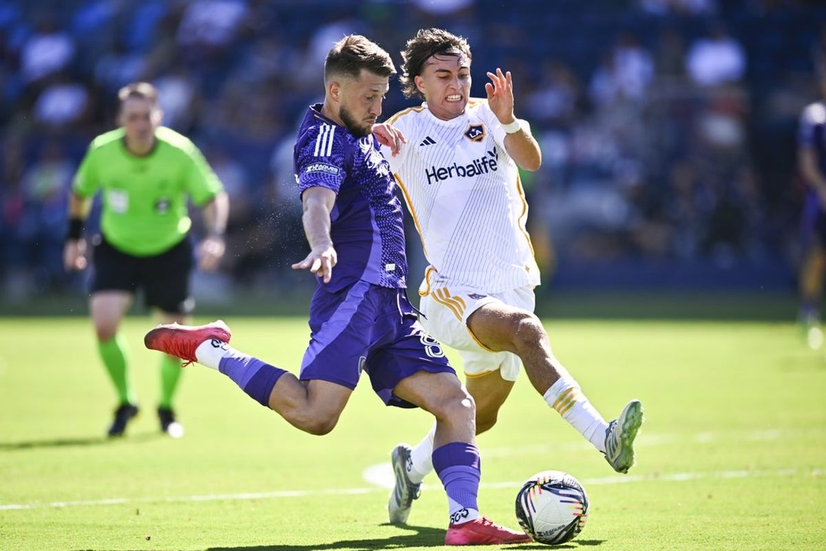 Aug 31, 2025; Carson, California, USA; Orlando City SC forward Marco Pasalic (87) shoots while LA Galaxy defender Julián Aude (3) defends during the second half at Dignity Health Sports Park. Mandatory Credit: Kelvin Kuo-Imagn Images