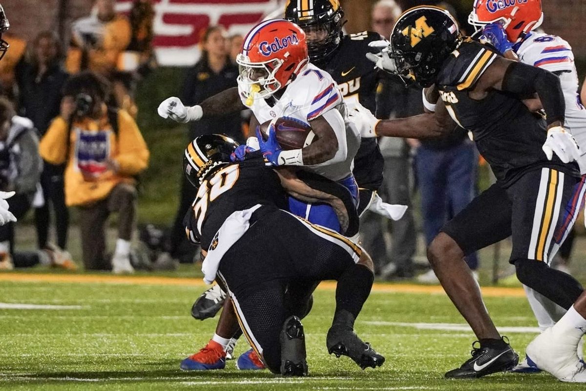 Nov 18, 2023; Columbia, Missouri, USA; Florida Gators running back Trevor Etienne (7) runs the ball as Missouri Tigers linebacker Chuck Hicks (30) makes the tackle during the first half at Faurot Field at Memorial Stadium.
