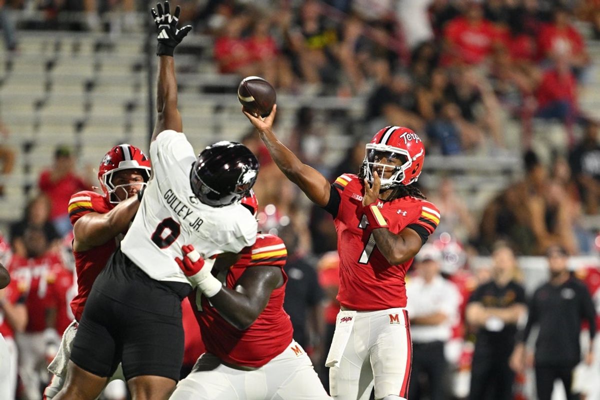 Sep 5, 2025; College Park, Maryland, USA;  Maryland Terrapins quarterback Malik Washington (7) passes over the reach of Northern Illinois Huskies defensive tackle Alvin Gulley Jr. (0) in the first half at SECU Stadium. Mandatory Credit: Jamie Sabau-Imagn Images