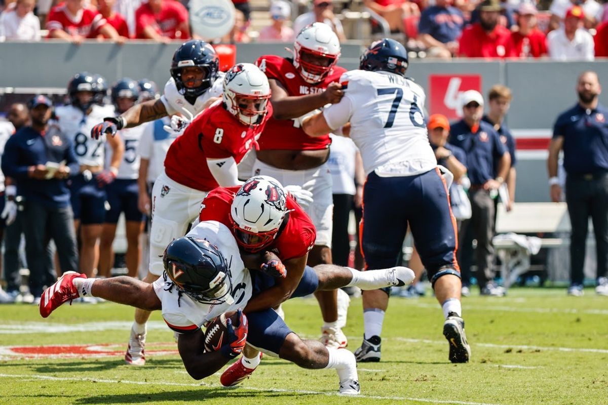 Sep 6, 2025; Raleigh, North Carolina, USA; North Carolina State Wolfpack offensive lineman Rico Jackson (64) tackles Virginia Cavaliers running back J'Mari Taylor (3) during the first half of the game at Carter-Finley Stadium. Mandatory Credit: Jaylynn Nash-Imagn Images