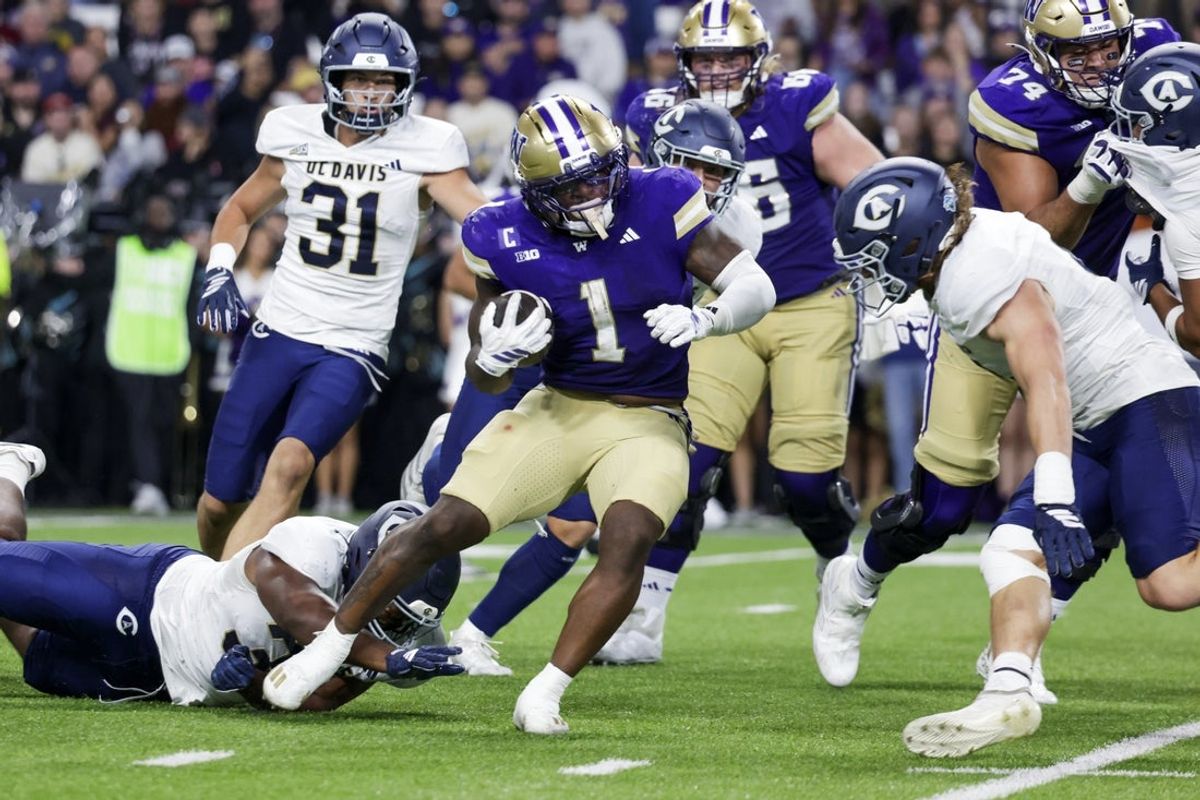 Sep 6, 2025; Seattle, Washington, USA; Washington Huskies running back Jonah Coleman (1) breaks a tackle attempt by UC Davis Aggies defensive lineman Derrell Porter (35) to rush for a touchdown during the second quarter at Husky Stadium. Mandatory Credit: Joe Nicholson-Imagn Images