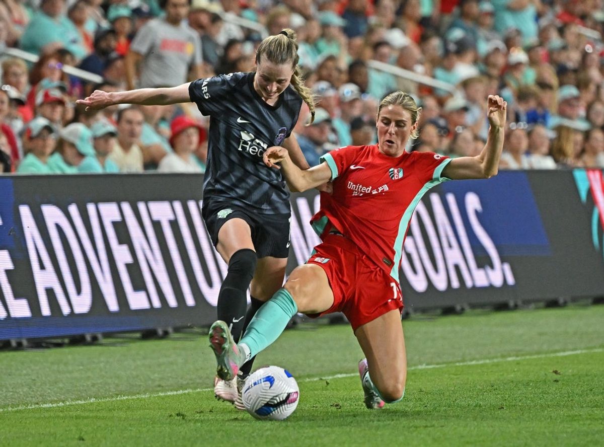 Sep 13, 2025; Kansas City, Missouri, USA;  Kansas City Current forward Brittany Ratcliffe (13) slides in for the ball against Washington Spirit defender Gabby Carle (14) in the second half at CPKC Stadium. Mandatory Credit: Peter Aiken-Imagn Images