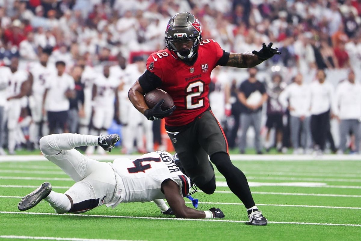 Sep 15, 2025; Houston, Texas, USA; Tampa Bay Buccaneers wide receiver Emeka Egbuka (2) runs for a touchdown as Houston Texans cornerback Kamari Lassiter (4) defends during the second quarter at NRG Stadium. Mandatory Credit: Troy Taormina-Imagn Images