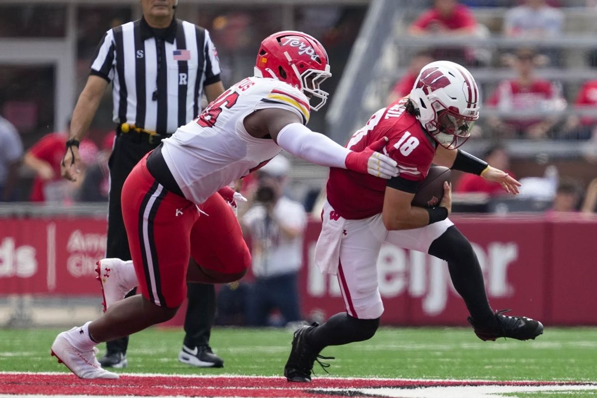 Sep 20, 2025; Madison, Wisconsin, USA;  Wisconsin Badgers quarterback Danny O'Neil (18) is tackled by jMaryland Terrapins defensive lineman Dillan Fontus (46)  during the second quarter at Camp Randall Stadium. Mandatory Credit: Jeff Hanisch-Imagn Images