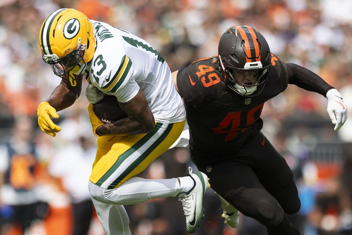 Sep 21, 2025; Cleveland, Ohio, USA; Green Bay Packers wide receiver Dontayvion Wicks (13) breaks a tackle by Cleveland Browns linebacker Carson Schwesinger (49) during the third quarter at Huntington Bank Field. Mandatory Credit: Scott Galvin-Imagn Images