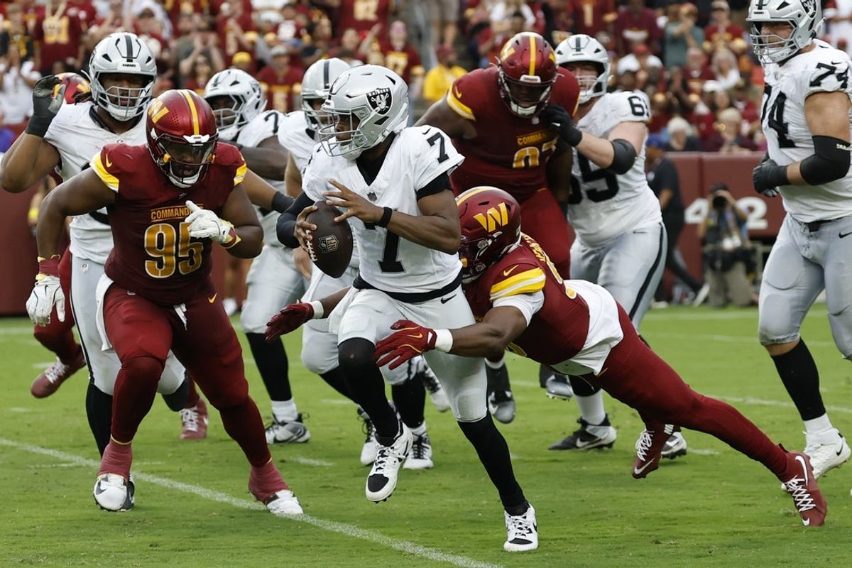 Sep 21, 2025; Landover, Maryland, USA; Las Vegas Raiders quarterback Geno Smith (7) is tackled by Washington Commanders defensive end Javontae Jean-Baptiste (90) during the third quarter at Northwest Stadium. Mandatory Credit: Geoff Burke-Imagn Images