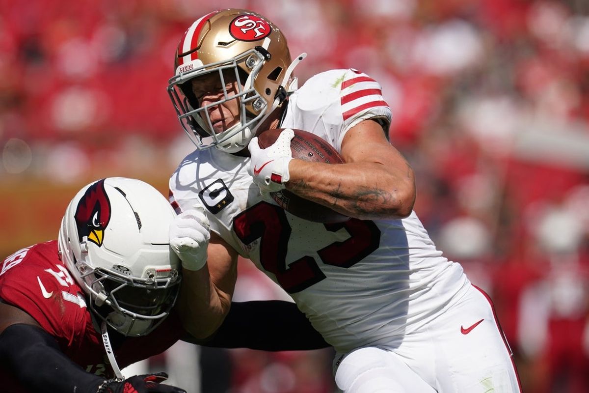 Sep 21, 2025; Santa Clara, California, USA; San Francisco 49ers running back Christian McCaffrey (23) carries the ball as Arizona Cardinals linebacker Akeem Davis-Gaither (27) defends during the first half at Levi's Stadium. Mandatory Credit: Cary Edmondson-Imagn Images