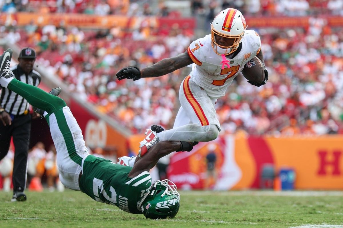Sep 21, 2025; Tampa, Florida, USA; Tampa Bay Buccaneers running back Bucky Irving (7) is tripped up by New York Jets cornerback Brandon Stephens (21) in the third quarter  at Raymond James Stadium. Mandatory Credit: Nathan Ray Seebeck-Imagn Images