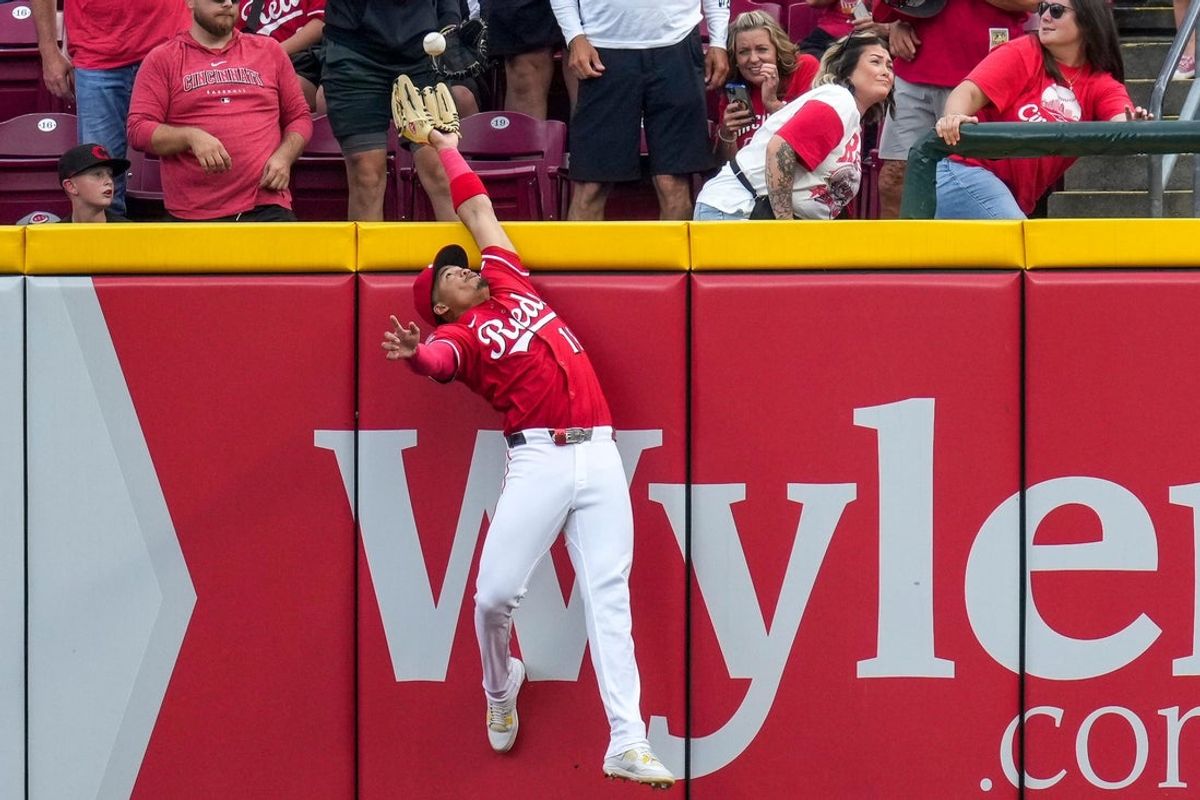 Cincinnati Reds third baseman Noelvi Marte (16) leaps to rob a home run over the wall from Pittsburgh Pirates right fielder Bryan Reynolds (10) in the ninth inning of the MLB National League game between the Cincinnati Reds and the Pittsburgh Pirates at Great American Ball Park in downtown Cincinnati on Thursday, Sept. 25, 2025. The Reds won, 2-1.